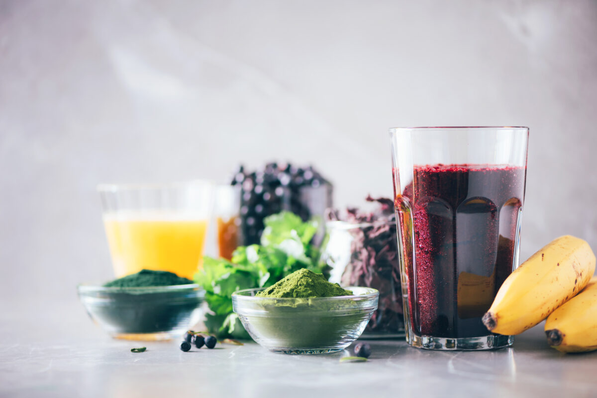 Healthy eating, alkaline diet, vegan concept. Blueberries, bilberry, barley grass juice, spirulina, orange juice, dulse and cilantro on marble background. Ingredients for heavy metals detox smoothie.